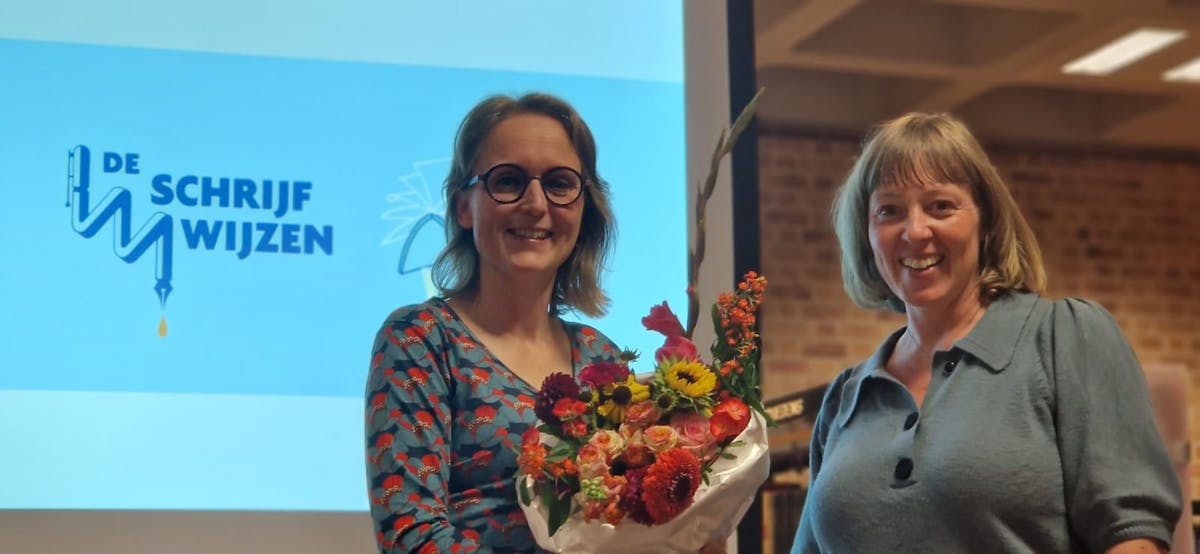 Hanneke Middelburg ontvangt bloemen van An Leenders, directeur van creatief schrijven